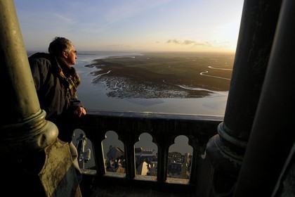 France, Manche, Mont Saint Michel, listed as World Heritage by UNESCO, Mr Antoine Bacchiarotti looking at the Apse and the bay from the spire at dawn