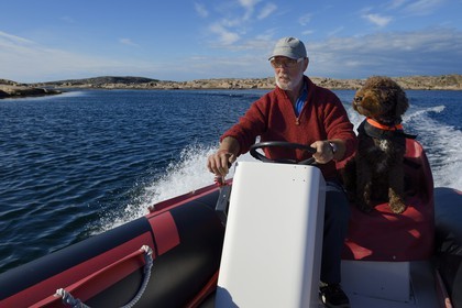 Suède, Västra Götaland, Smögen, Cyril et son chien Simpson à bord de son zodiac