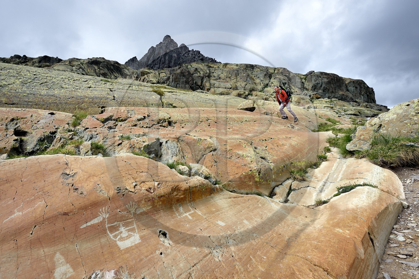 France, Alpes-Maritimes (06), parc national du Mercantour, vallée des Merveilles parsemée de milliers de gravures rupestres de l'Age de bronze, randonneur au dessus de la figure anthropomorphe gravée sur la roche dite du Sorcier sur les dalles de schiste jaune des chiappes