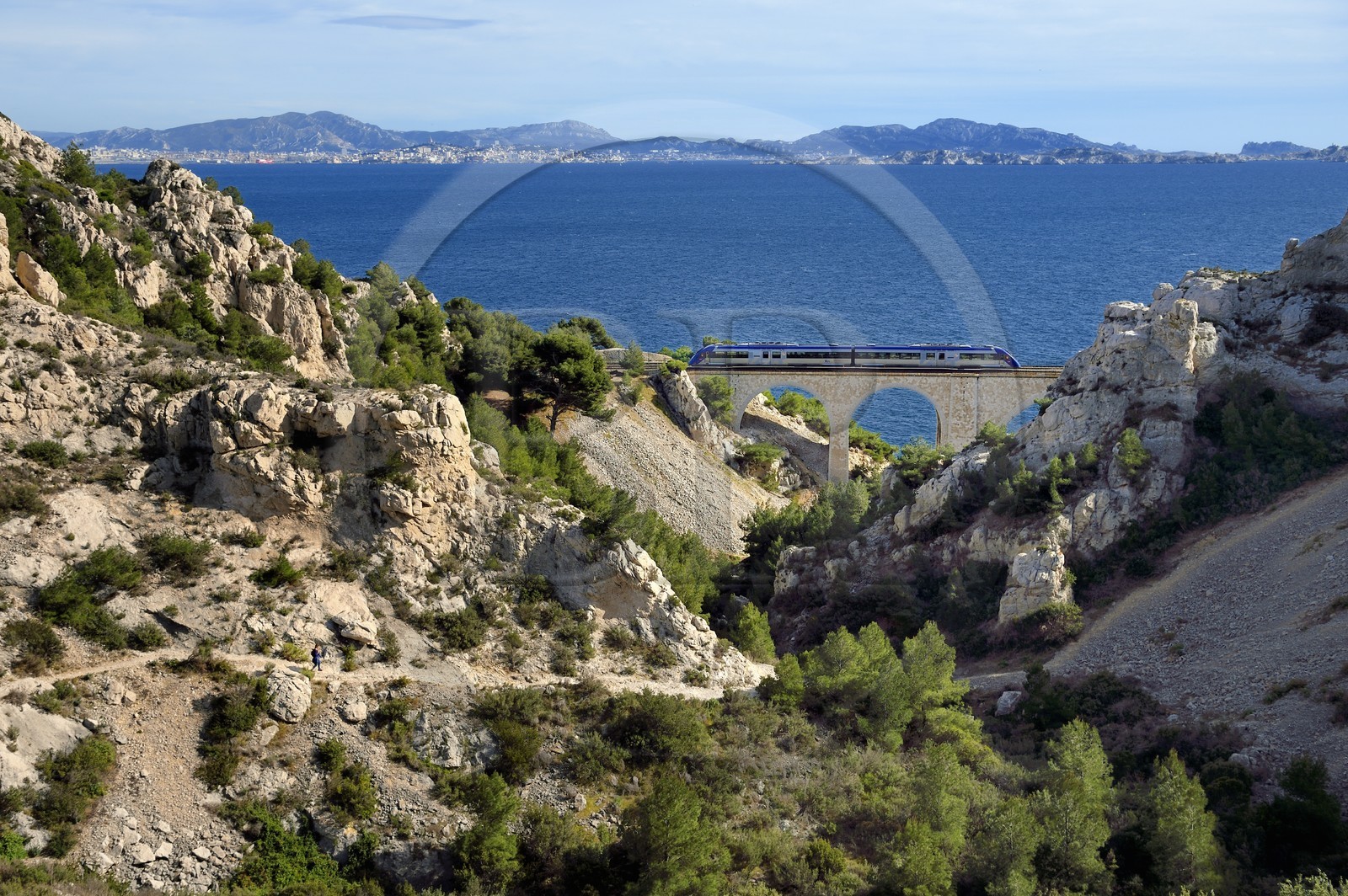 France, Bouches du Rhone, Le Rove towards Marseille, the Cote Bleue (Blue Coast), hike from Niolon to Cap Méjean along the Customs Trail, hiker descending to the Jonquier calanque railway bridge and the city of Marseille in the background