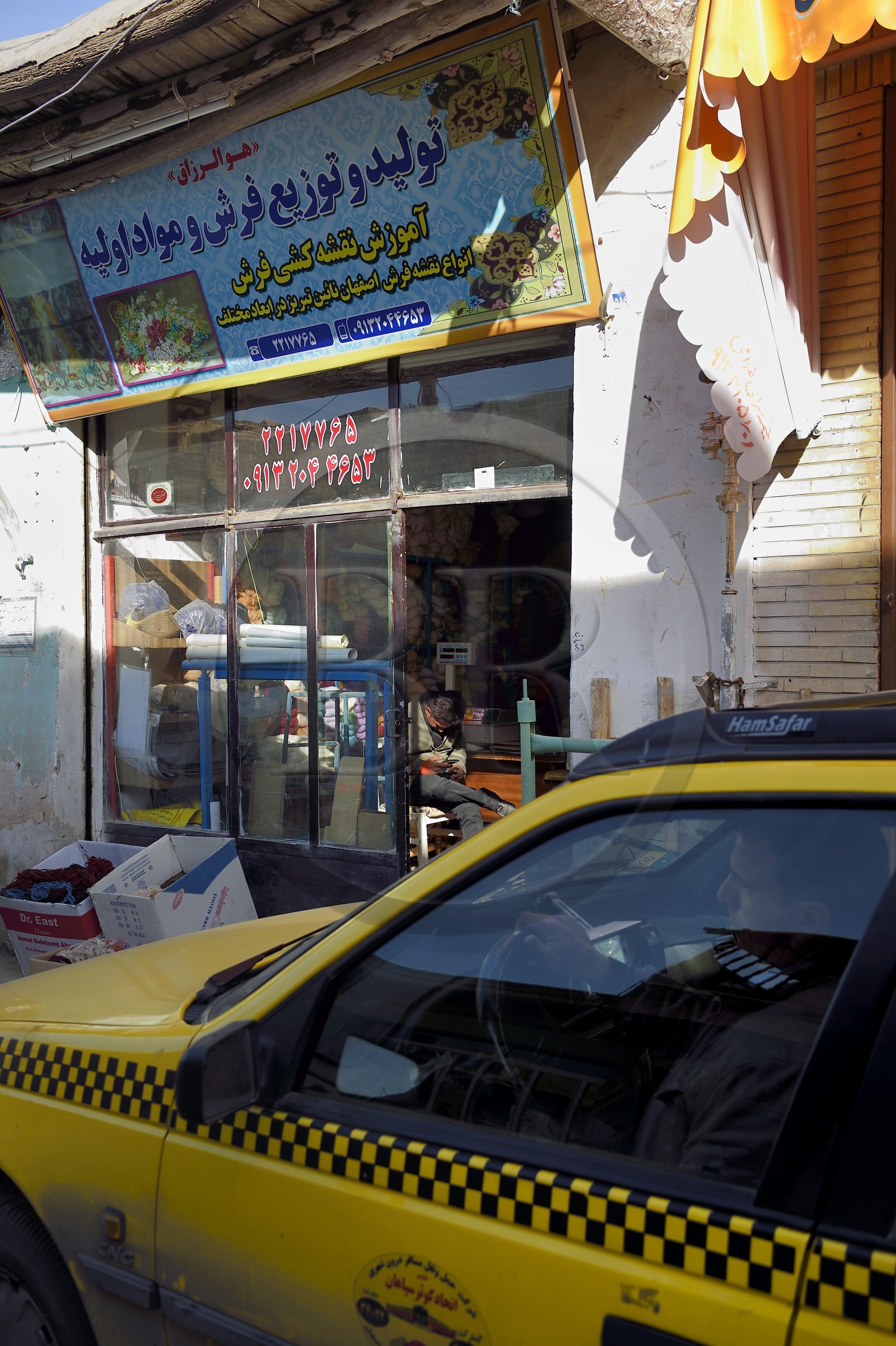 Iran, province d'Ispahan, Ispahan, taxi devant une boutique de tissus