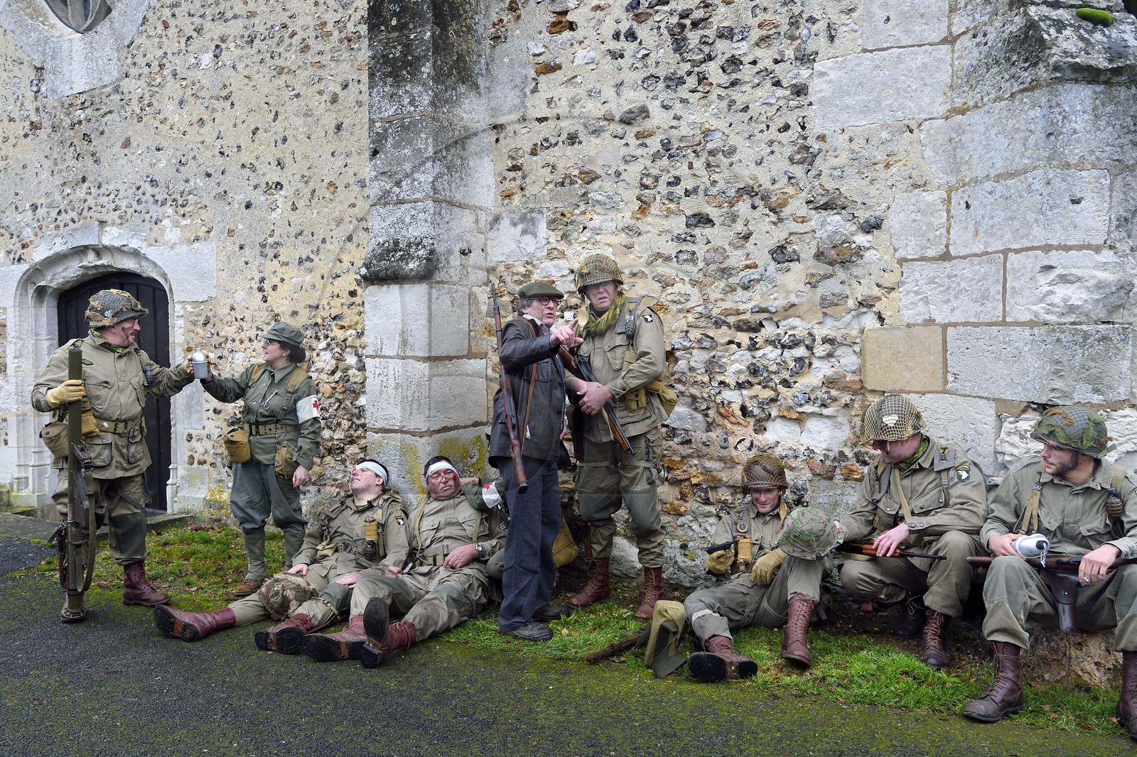 France, Eure, Chambray, Allied Reconstitution Group (US World War 2 and french Maquis historical reconstruction Association), reenactors in uniform of the 101st US Airborne Division and partisans of the French Forces of the Interior (FFI) resting in front of the church