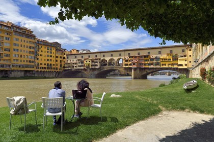 Italy, Tuscany, Florence, listed as World Heritage by UNESCO, the Ponte Vecchio seen from the Societa Canottieri Firenze (Florence Rowing Club), club members having a rest on the edge of the Arno River