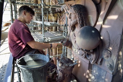 France, Bas-Rhin (67), Strasbourg, vieille ville classée au Patrimoine Mondial de l'UNESCO, la cathédrale Notre-Dame, chantier de restauration du Portail du Jour du jugement, Christ redempteur au dessus du Roi Salomon, nettoyage de la sculture à la brosse à dent par un apprenti tailleur de pierre