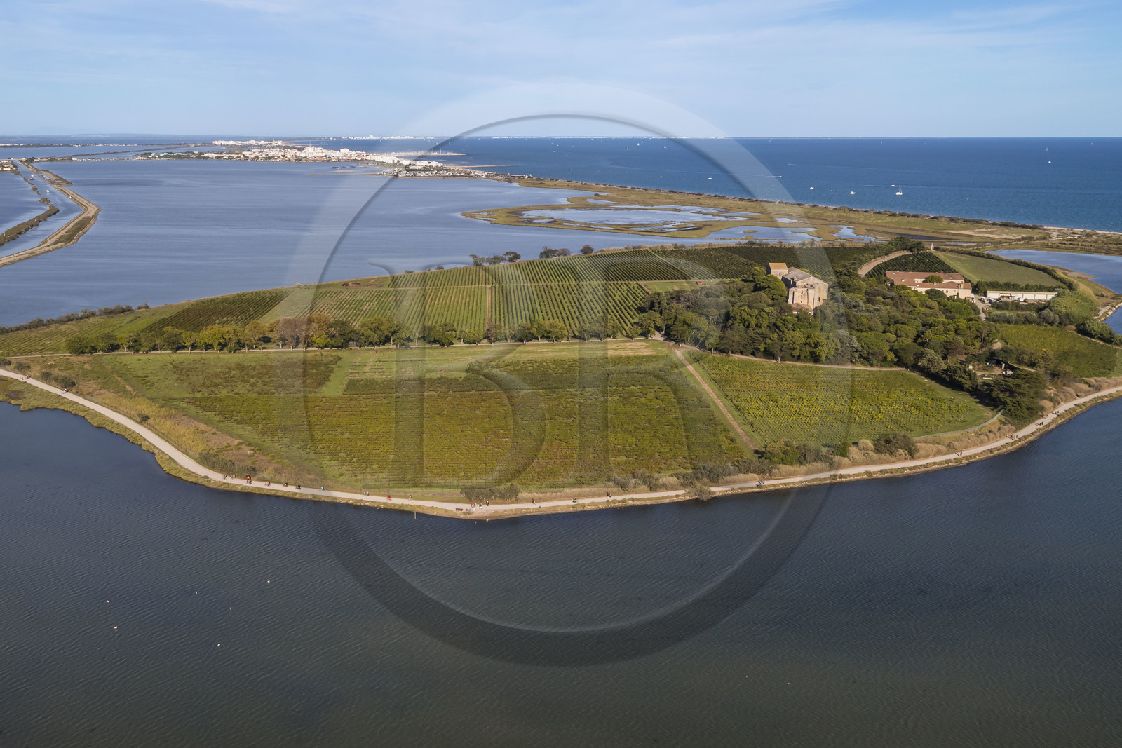 France, Herault, Villeneuve les Maguelone (Palavas Les Flots), Saint-Pierre-et-Saint-Paul de Maguelone cathedral from the 12th and 13th centuries surrounded by vineyards on its island, the Prévost pond and Palavas Les Flots in the background (aerial view)