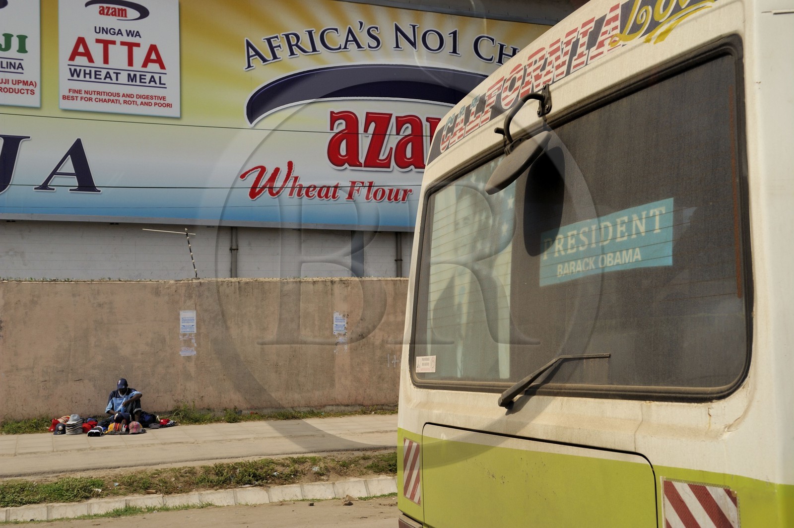 Tanzania, Dar es-Salaam, hat salesman on the sidewalk and poster of Barack Obama on the back of a bus