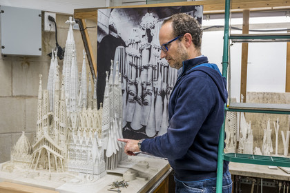 Espagne, Catalogne, Barcelone, quartier de l'Eixample, basilique de la Sagrada Familia de l'architecte du modernisme catalan Antoni Gaudi classée Patrimoine Mondial de l'UNESCO, l'atelier maquettes, l'architecte et coordinateur de l'équipe des artistes et des maquettistes Jeronimo Buxareu Padros présente les prochains travaux à entreprendre, la future facade de la Gloire face à lui et la photo de la maquette originale de Gaudi en arrière plan