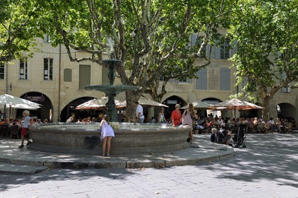France, Gard (30), Uzès, classée ville d'art et d'histoire, fontaine de la Place aux Herbes entourée de maisons à arcades et ses terrasses de café