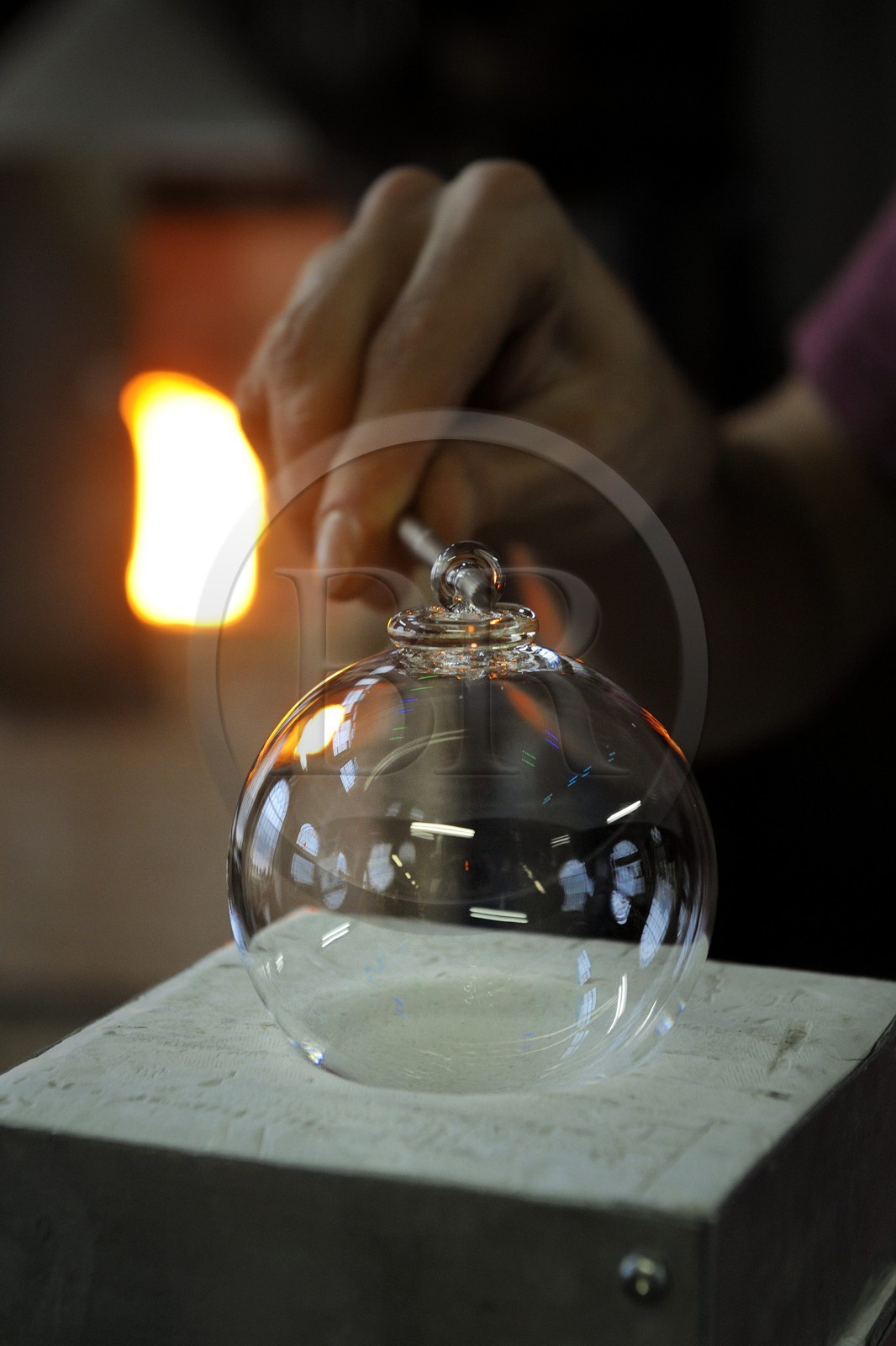 France, Moselle (57), Meisenthal, Thibaut souffleur au Centre international d’Art verrier (CIAV), fabrication d'une boule de Noël en verre. Une petite dentelle de verre tournée autour d’une petite baguette en fer va faire office d’attache qui est scellée à chaud