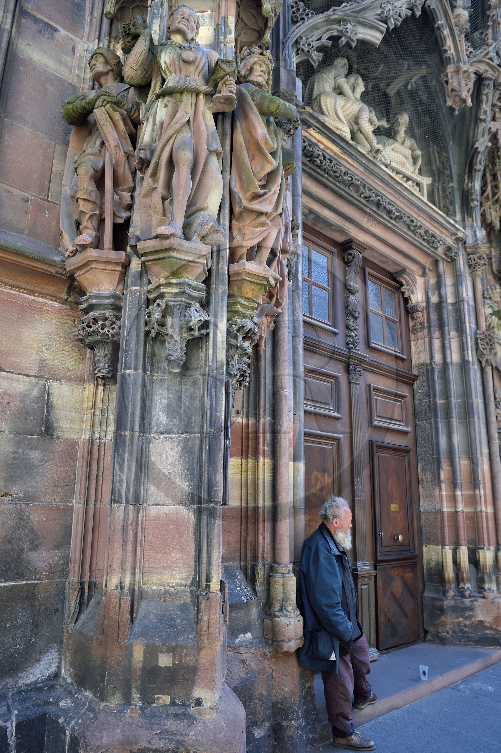 France, Bas-Rhin (67), Strasbourg, vieille ville classée au Patrimoine Mondial de l'UNESCO, la cathédrale Notre-Dame, portail de Saint-Laurent au transept nord avec l'adoration des Rois Mages du sculpteur Johan von Ach, mendiant attendant la sortie de la messe