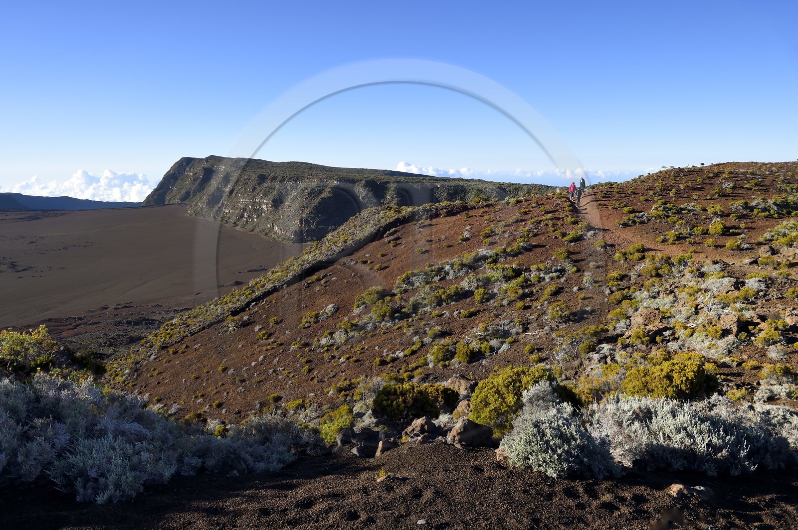 France, Ile de la Reunion, Parc National de la Réunion classé Patrimoine Mondial de l'UNESCO, sur les pentes du volcan de Piton de la Fournaise, randonneurs sur le sentier de l'oratoire Ste Thérèse au dessus de la Plaine des Sables que l'on aperçoit en contrebas