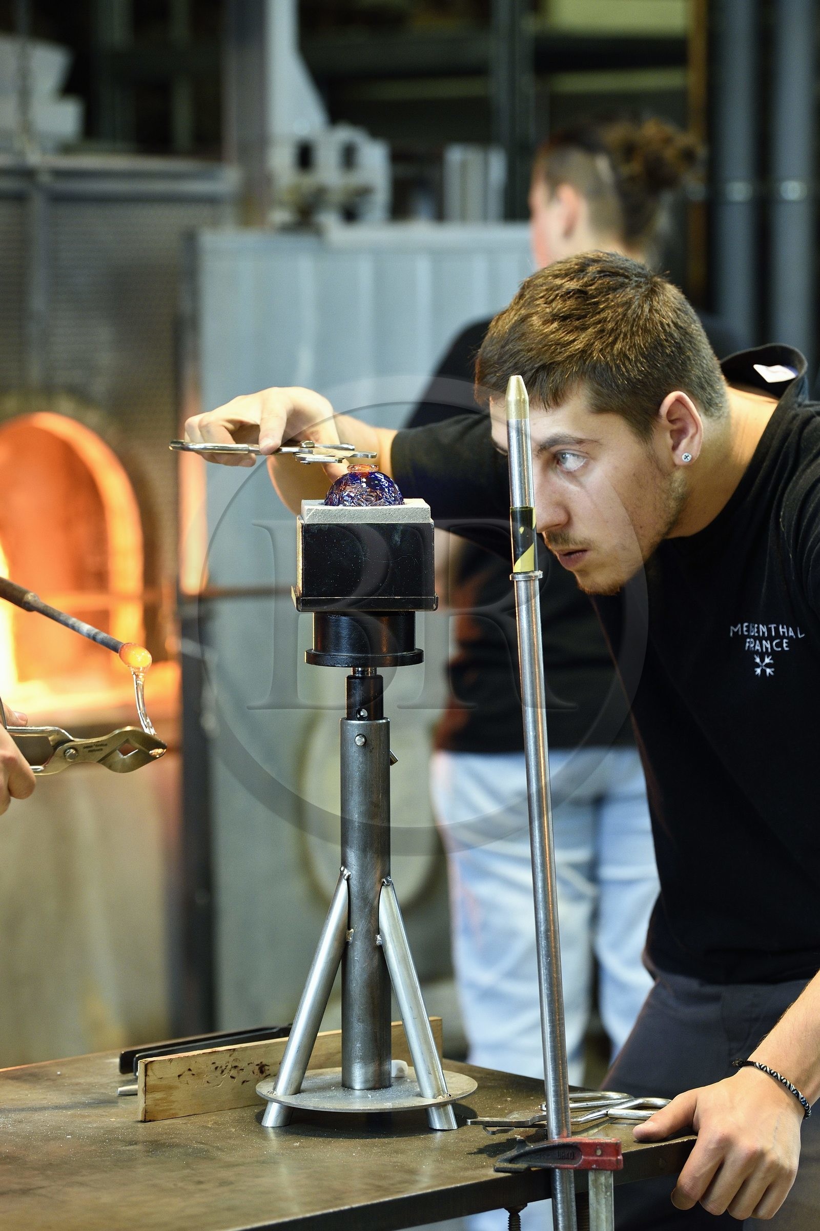 France, Moselle (57), Meisenthal, Centre international d’Art verrier (CIAV), l'atelier de soufflage, fabrication artisanale d'une boule de Noël, pose de la pastille pour la création du crochet en verre