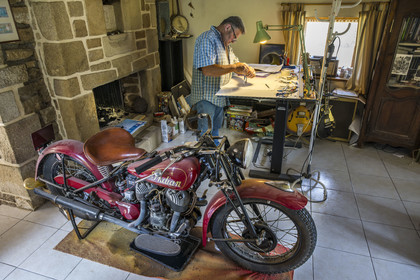France, Morbihan (56), Locoal-Mendon, le sculpteur et tailleur de pierre Gueho Patrick dans son bureau avec une moto Indian scout de 1940
