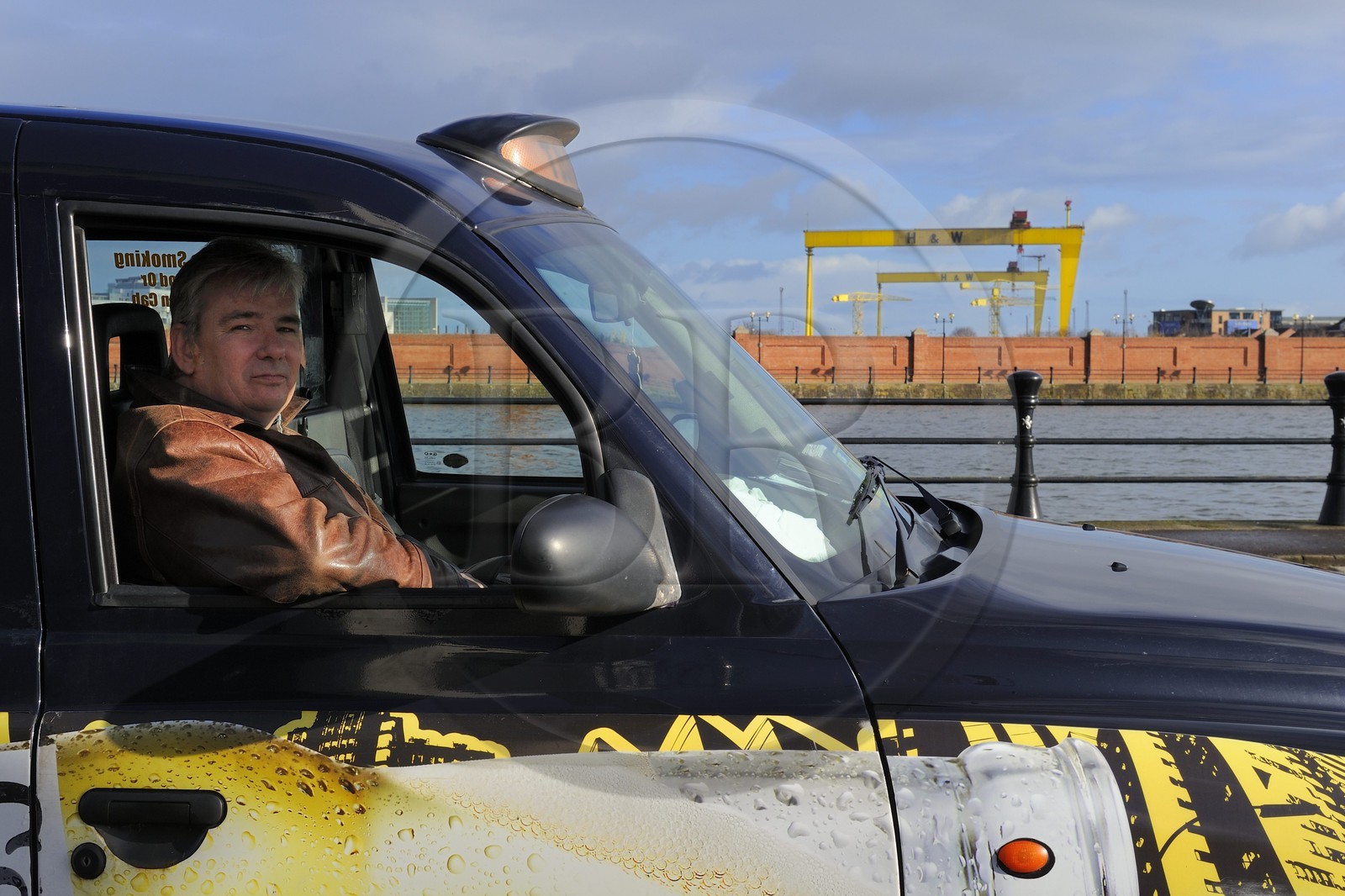 Royaume-Uni, Irlande du Nord, Belfast, Billy Scott dans son Black Cab devant les deux portiques de Harland and Wolff surnommés Samson et Goliath qui sont devenus un repère de la ville