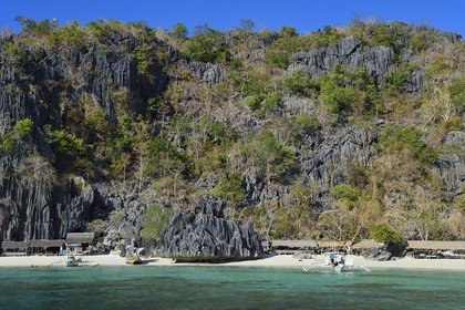 Philippines, Calamian Islands dans le nord de Palawan, Coron Island Natural Biotic Area, pirogue à balancier et plage de Banul Beach au pied des murs géants des falaises de calcaire