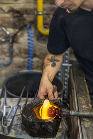 France, Moselle (57), Meisenthal, Centre international d’Art verrier (CIAV), l'atelier de soufflage, le souffleur régularise la masse au marbre tout en effectuant une rotation continue de sa canne et préparation de la paraison avant le passage au moule