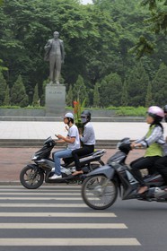 Vietnam, Hanoï, circulation en moto dans la vieille ville devant la statue de Lénine