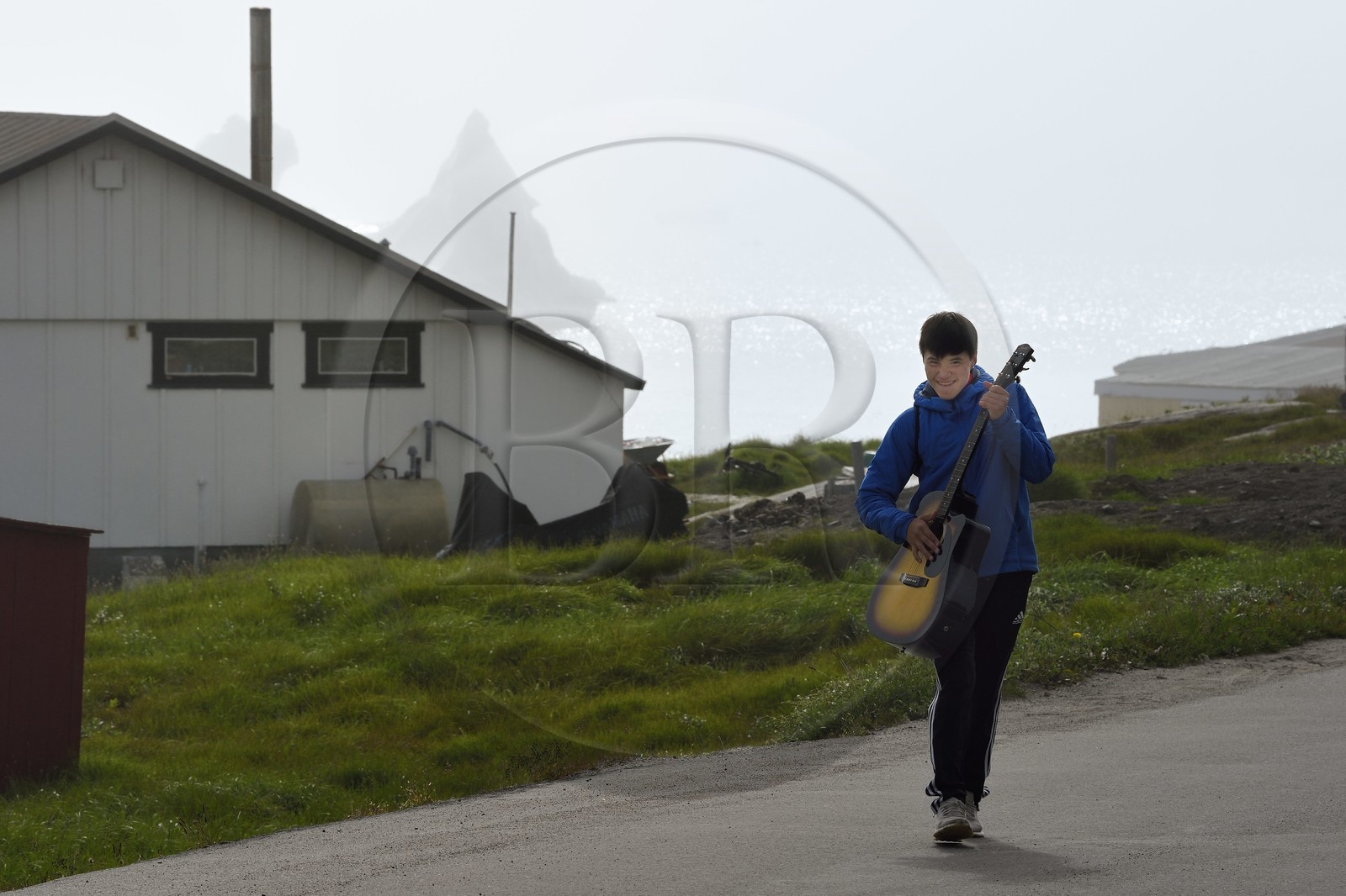 Groenland, cote ouest, Ile de Disko, Qeqertarsuaq, jeune inuit avec sa guitare et icebergs en arrière plan