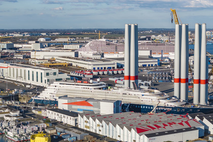France, Loire Atlantique, Saint Nazaire, the construction site of the luxury super-yacht Ritz-Carlton Luminara in the Joubert dry dock in the foreground, the wind turbine towers are stored before embarkation, the 333m MSC World America cruise ship built by Chantiers de l'Atlantique in the background (aerial view)