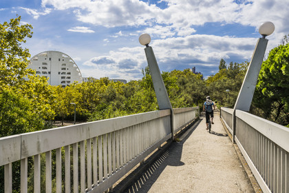 France, Hérault (34), La Grande-Motte, labellisé patrimoine du XXème siècle, quartier du Couchant à l'ouest du port, cycliste franchissant la passerelle dite des Monstres