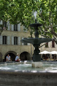 France, Gard (30), Uzès, classée ville d'art et d'histoire, fontaine de la Place aux Herbes entourée de maisons à arcades et ses terrasses de café