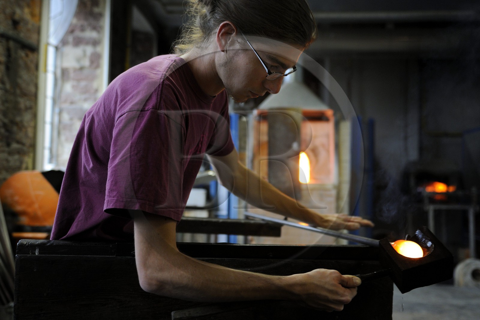 France, Moselle, Meisenthal, glassblower Thibaut at the Centre international d'Art verrier (CIAV) (international glass centre) is using a wooden tool called mailloche to round up the glass and make a christmas bowl made of glass which is even