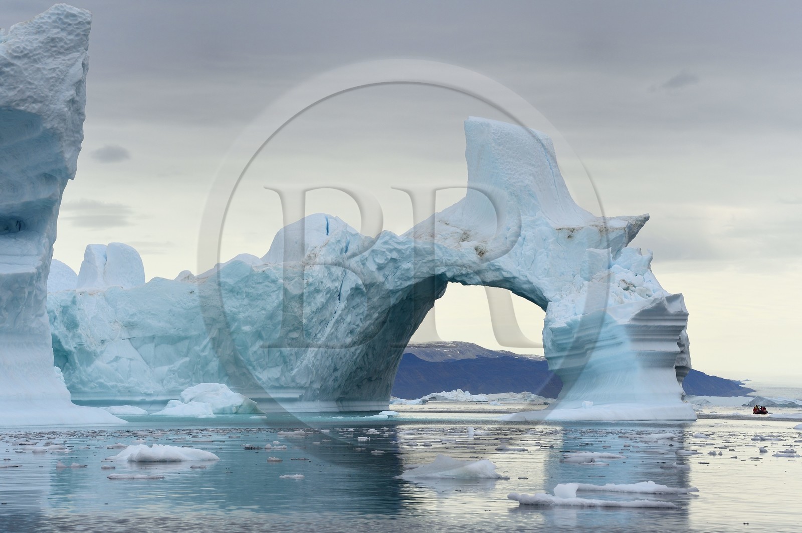Groenland, cote Nord-Ouest, mer de Baffin, Inglefield Fjord vers Qaanaaq, iceberg formant un arche et un PolarCirkel boat (zodiac) d'exploration du bateau de croisière MS Fram de la compagnie Hurtigruten