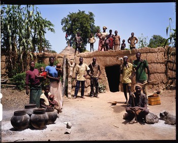 Burkina Faso, province de Poni, pays des Lobi, Loropéni, paysans posant avec la houe dans la cour de ferme devant la maison principale