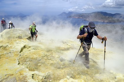 Italie, Sicile, iles Eoliennes, classées Patrimoine Mondial de l'UNESCO, ile de Vulcano, randonneurs dans l'ascension du cratère du volcan della Fossa à travers les fumerolles soufrées, l'Ile de Lipari puis Ile de Salina en arrière plan