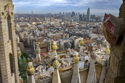 Espagne, Catalogne, Barcelone, quartier de l'Eixample, basilique de la Sagrada Familia de l'architecte du modernisme catalan Antoni Gaudi classée Patrimoine Mondial de l'UNESCO, sommets surmontés de mosaïques en forme de fruits entourant le chantier sur le toit de la nef à l'arrière de la future facade de la Gloire, la Torre Agbar de l'architecte Jean Nouvel en arrière plan