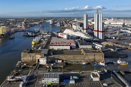 France, Loire-Atlantique (44), Saint-Nazaire, l’écluse Est et l'écluse fortifiée de l'ancienne base sous-marine allemande construite lors de la dernière guerre mondiale au premier plan et le chantier du super-yacht de luxe Ritz-Carlton Luminara dans la forme Joubert, les tours d'éoliennes à droite sont stockées avant embarquement, le paquebot de 333m MSC World America construit par les Chantiers de l'Atlantique en arrière plan (vue aérienne)