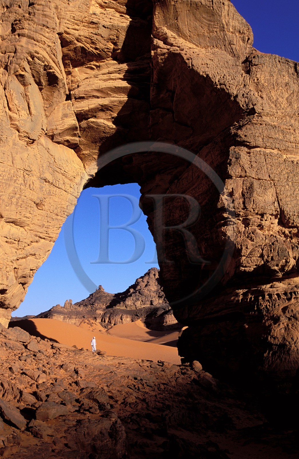 Libye, région du désert, Le Fezzan (Sahara), Touareg sous l'arche (en grès) de Afazedjar dans la Tadrart-Akakus