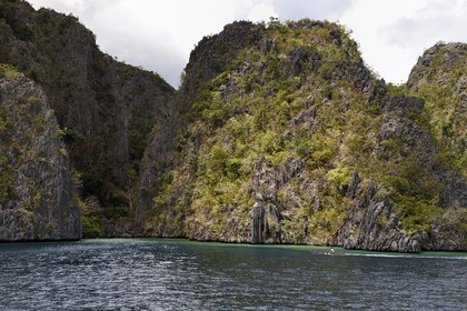 Philippines, Calamian Islands dans le nord de Palawan, Coron Island Natural Biotic Area, pirogue à balancier dans un lagon au pied des falaises de calcaire du Permien d'origine jurassique