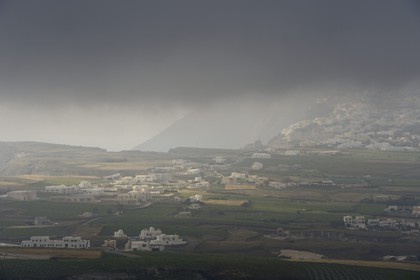 Greece, Cyclades, Aegean Sea, Santorini (Thira or Thera), clouds are often stuck on the top of the caldera cliffs, vineyards at the foot of the village of Thira