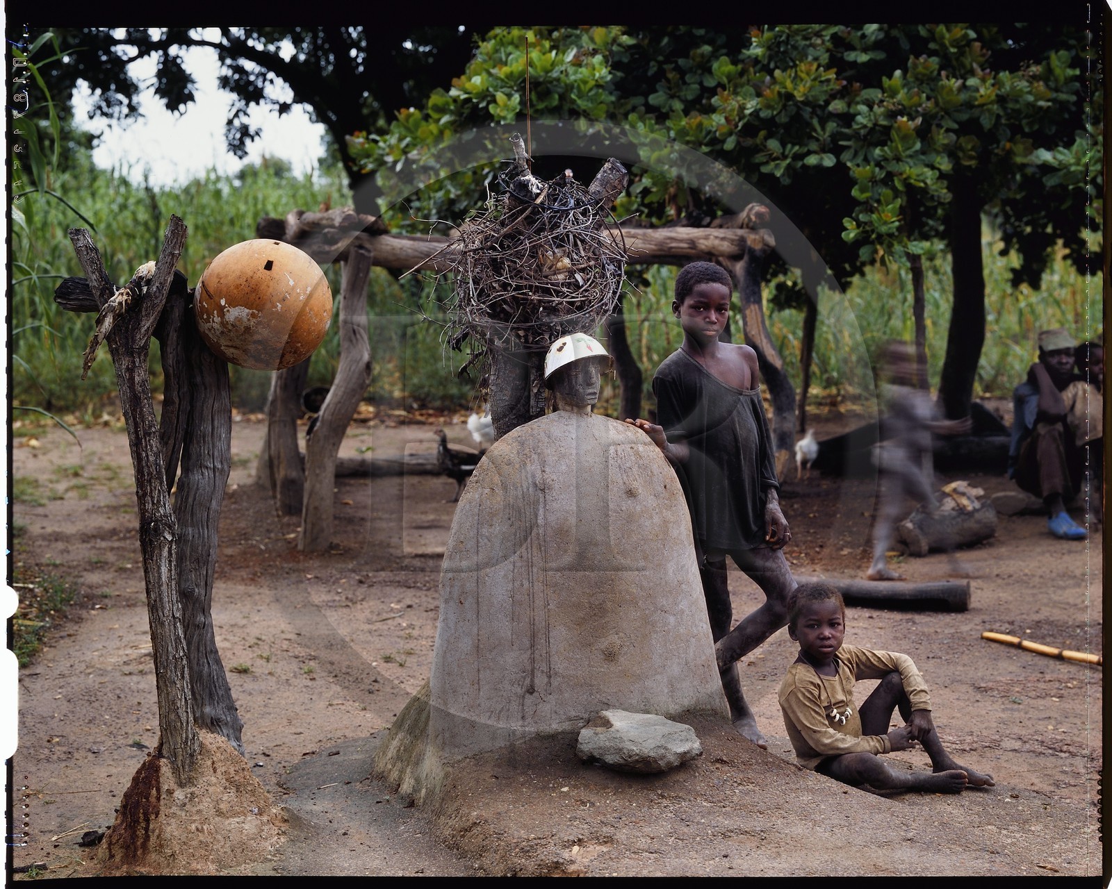 Burkina Faso, province de Poni, pays des Lobi, Loropéni, enfants posant à coté des deux autels principaux de la maison de leur père, liens avec les esprits et les ancetres