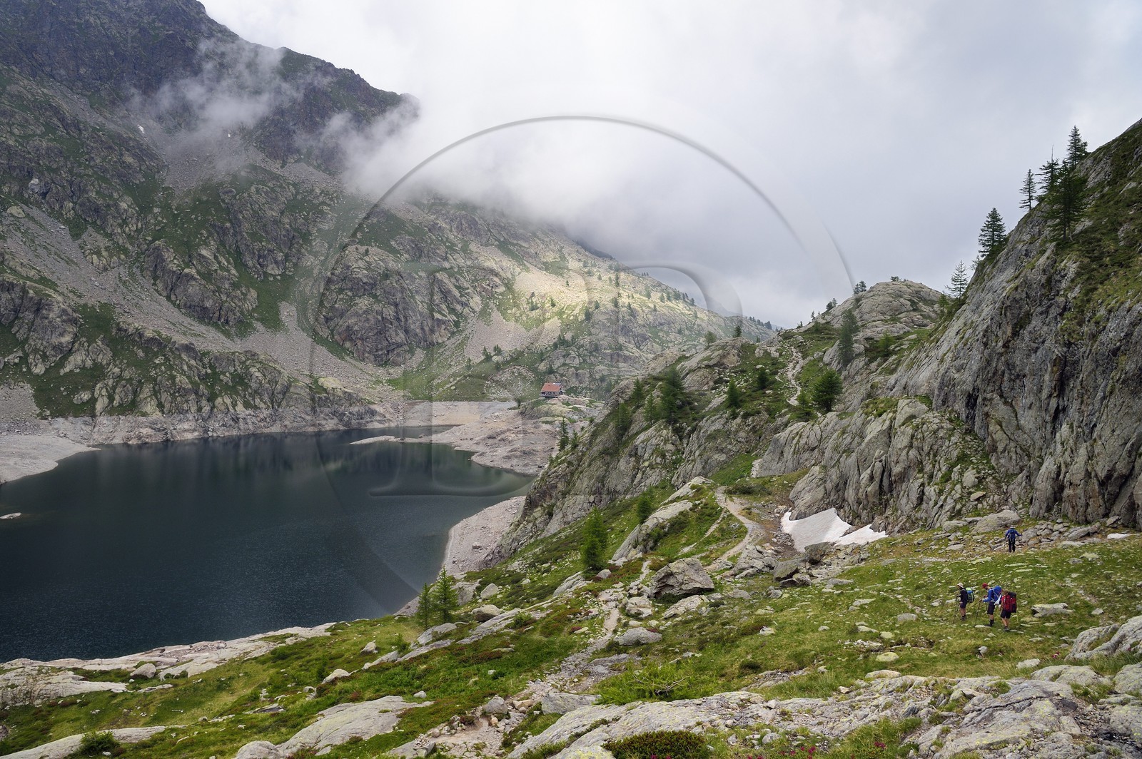 France, Alpes-Maritimes (06), parc national du Mercantour, vallée de la Valmasque, randonneurs sur le sentier de randonnée au dessus du lac Vert et le refuge de la Valmasque (FFCAM) à 2233m en arrière plan