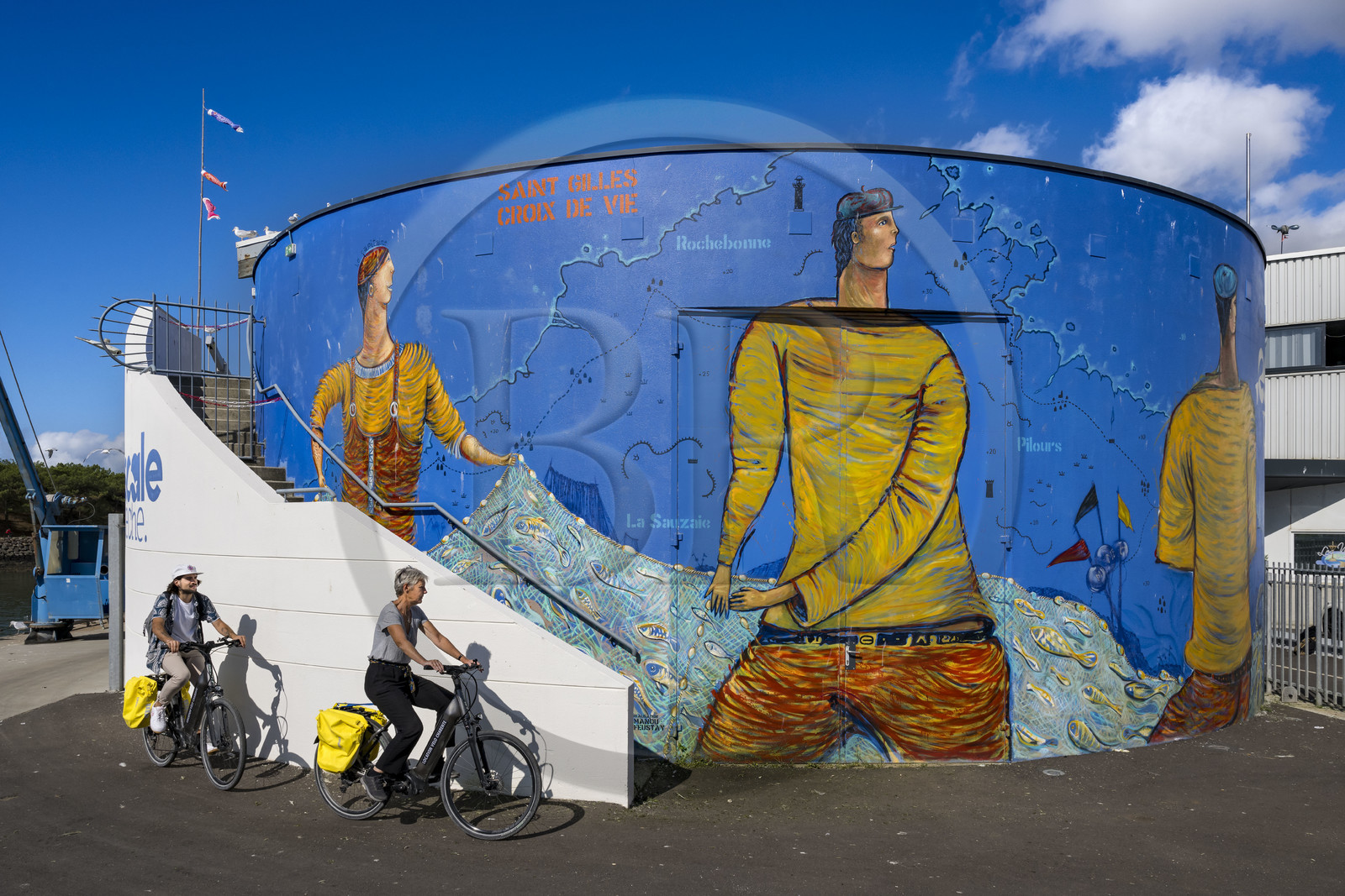 France, Vendée (85), Saint-Gilles-Croix-de-Vie, cyclistes passant devant la peinture murale sur la facade de la criée réalisée par Manou Feustay