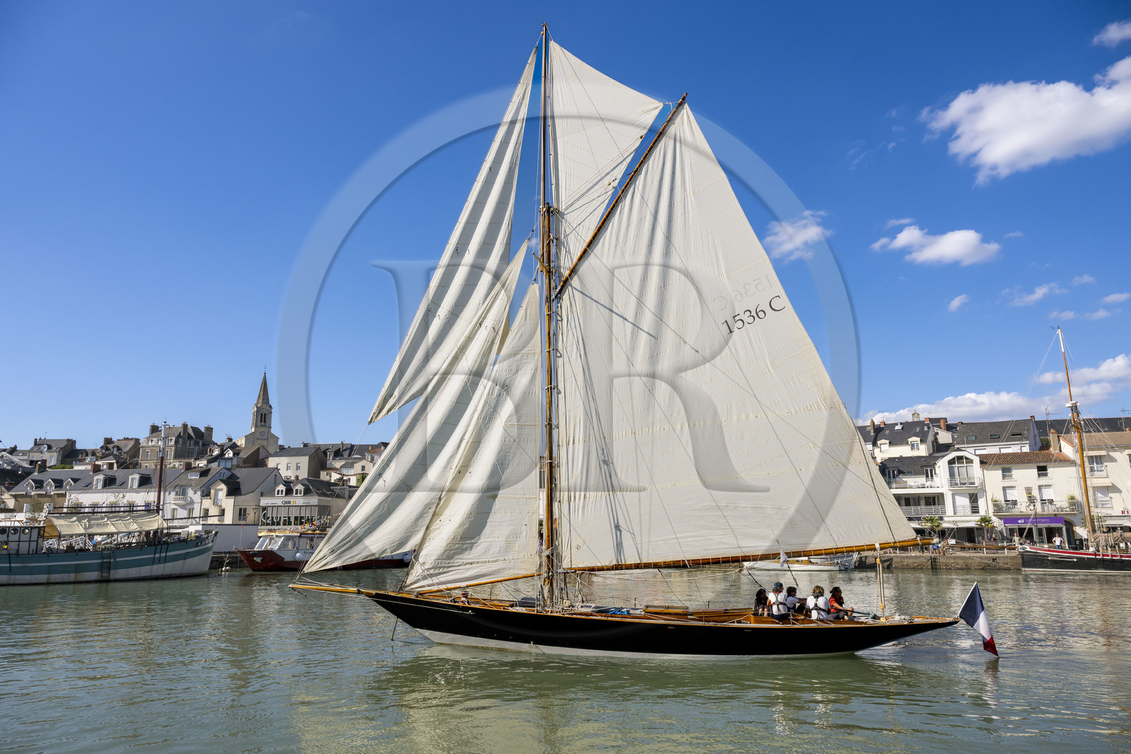 France, Loire Atlantique, Pornic, the Pen Duick sailboat leaving the port under sail, the Saint-Gilles church in the background