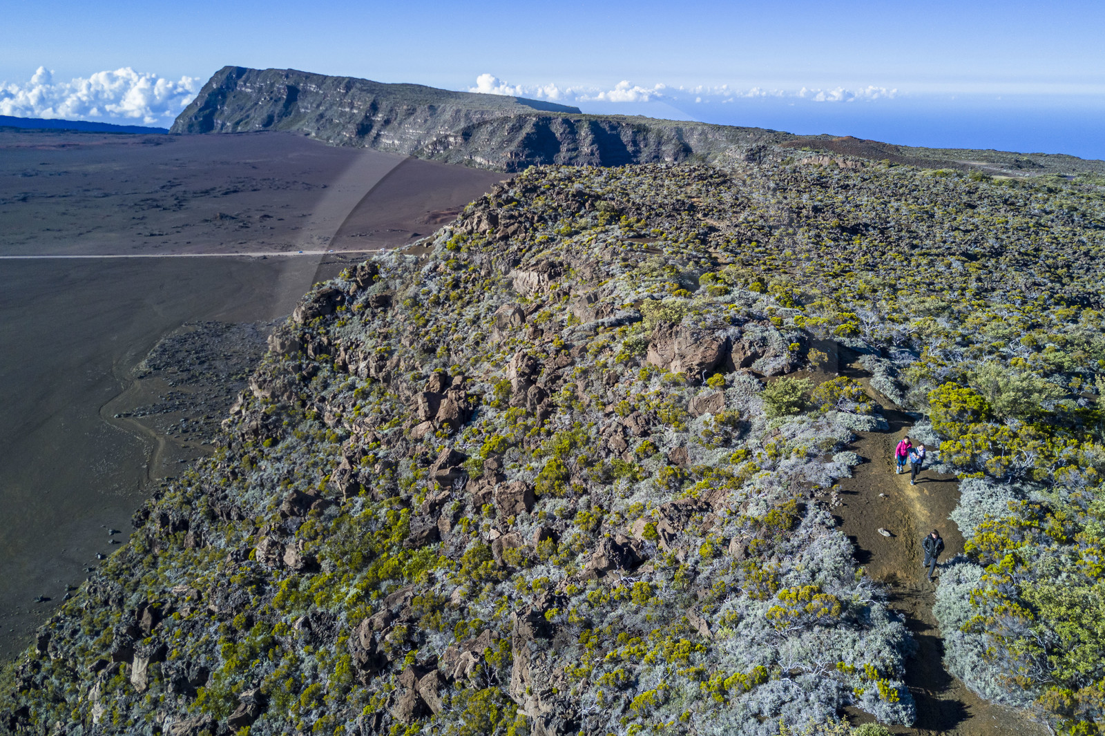 France, Reunion island (French overseas department), Reunion National Park listed as World heritage by UNESCO, on the slopes of the Piton de la Fournaise volcano, hikers on the Ste Therese oratory trail above the Plaine des Sables that we can see below (aerial view)