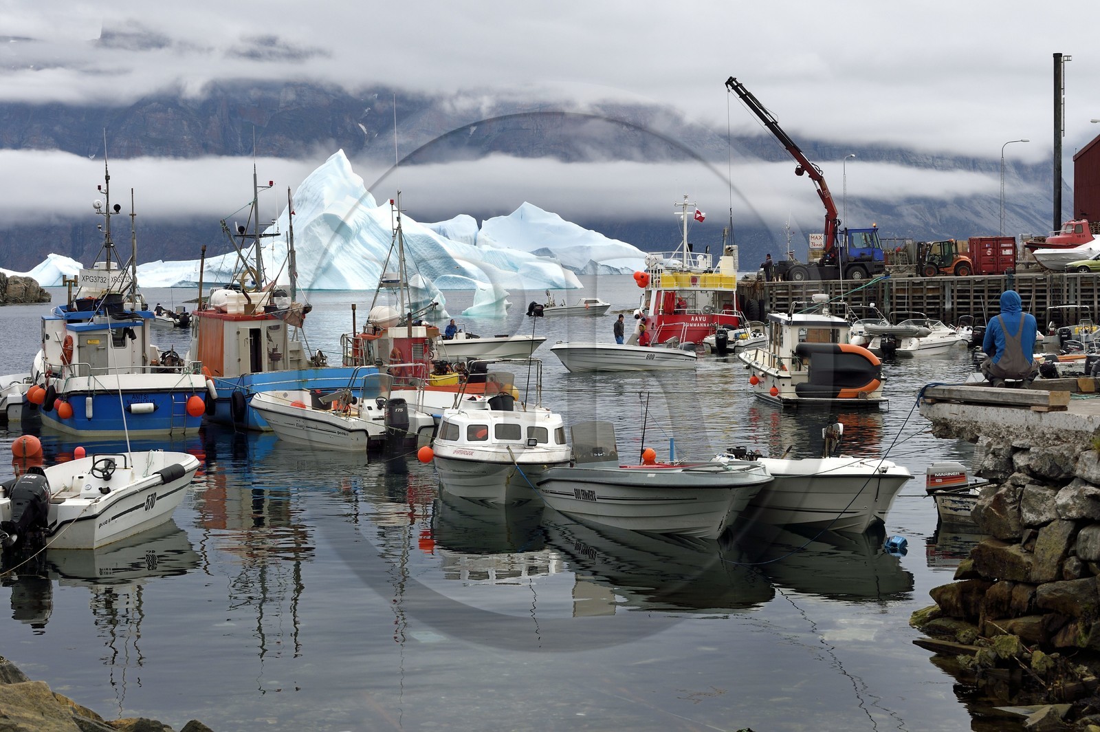 Groenland, cote ouest, Uummannaq, bateau de pêche déchargeant dans le port et icebergs en arrière plan
