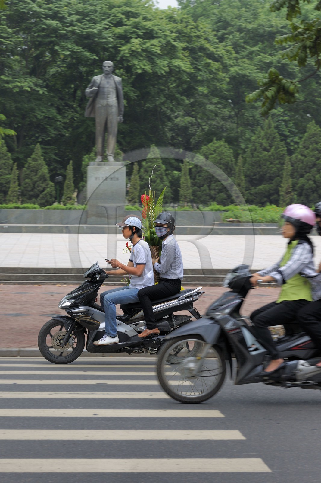 Vietnam, Hanoï, circulation en moto dans la vieille ville devant la statue de Lénine