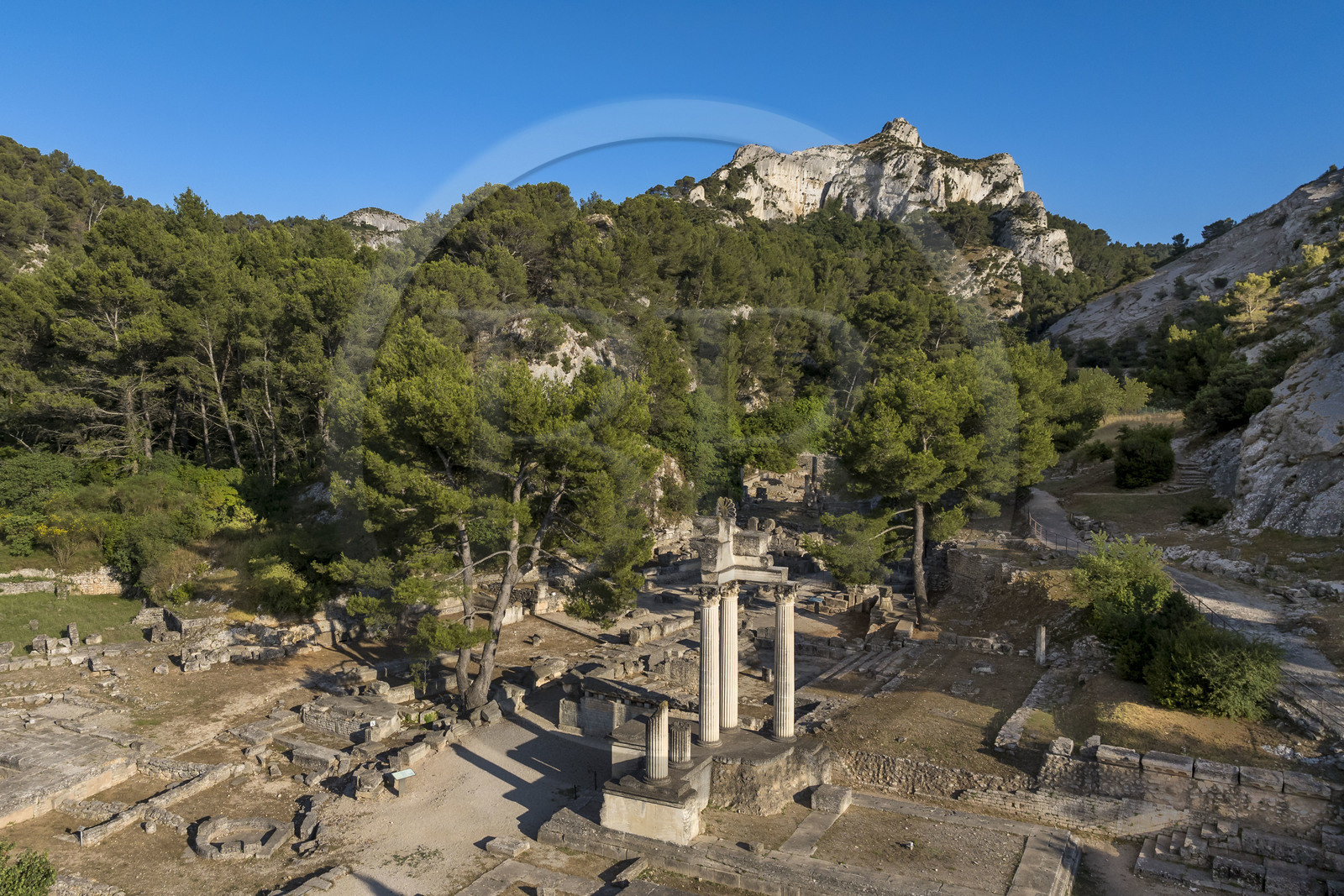 France, Bouches-du-Rhône (13), Parc Naturel Régional des Alpilles, Saint-Rémy-de-Provence, site archéologique de Glanum au pied du massif des Alpilles, colonnes et entablement reconstitués du petit temple géminé du premier forum au premier plan (vue aérienne)
