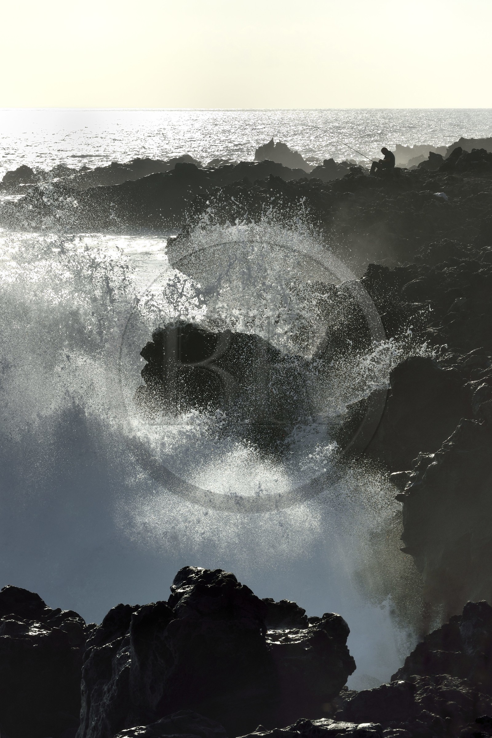 France, Ile de la Reunion, L'Etang Salé les Bains, la côte entre Le Gouffre et l'Etang du Gol, roches noires basaltiques d'origine volcanique tourmentées par l'océan, pêcheur à la ligne