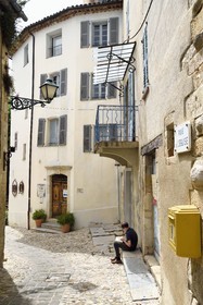 France, Var, Seillans, labelled Les Plus Beaux Villages de France (The Most Beautiful Villages of France), Maison Waldberg in the middle contains the donations of Max Ernst, Dorothea Tanning and Stan Appenzeller, Bargemon gallery owner Guy Beddington reads a book sitting in the lane