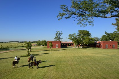 Argentine, province de Buenos Aires, San Antonio de Areco, estancia La Bamba de Areco, gauchos à cheval passant devant l'étable des chevaux utilisés pour le polo