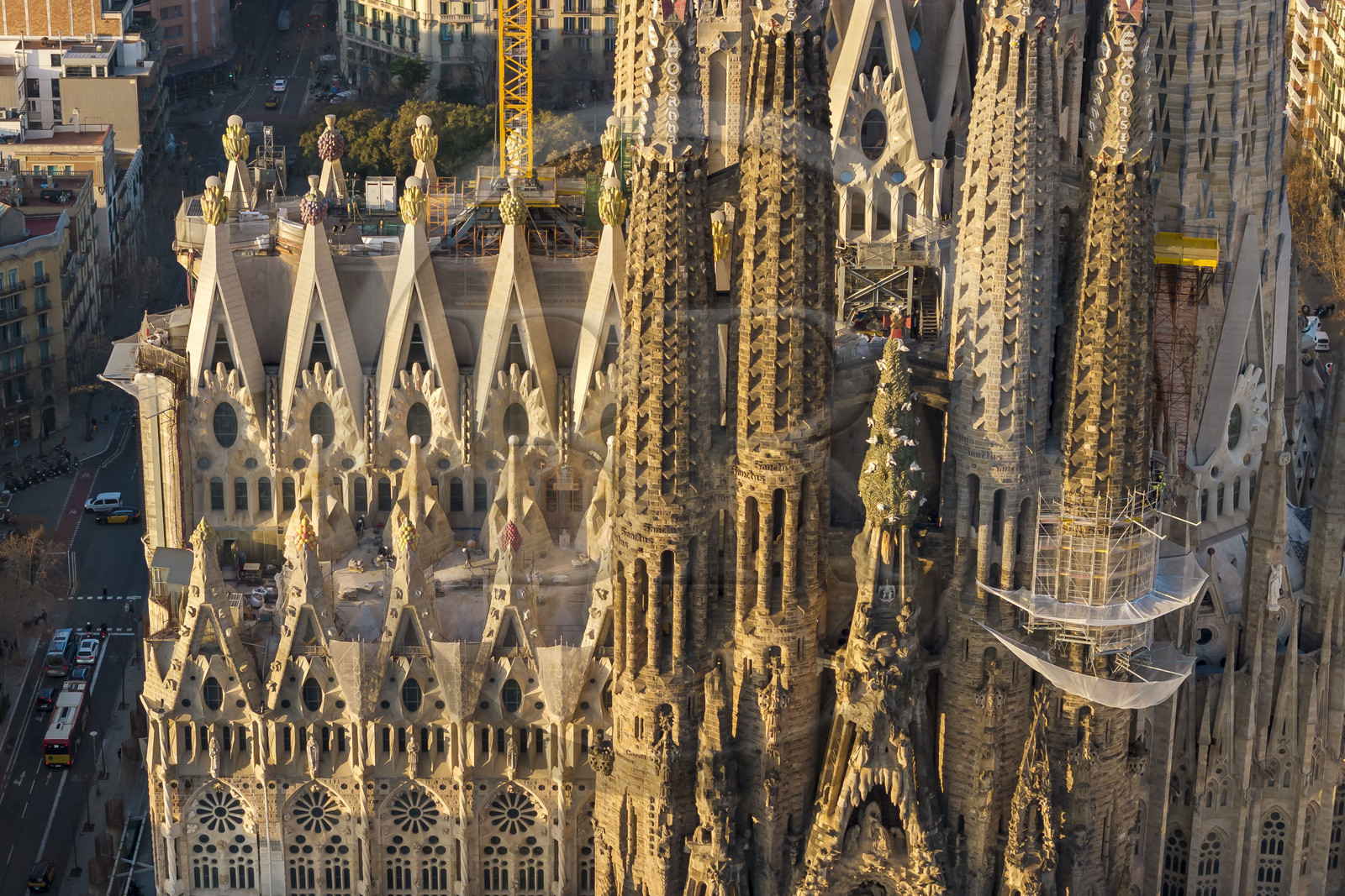 Spain, Catalonia, Barcelona, Eixample district, Sagrada Familia basilica by Catalan modernist architect Antoni Gaudi, listed as a UNESCO World Heritage Site, peaks topped with mosaics in the shape of fruits surrounding the construction site on the roof of the nave here on the Passion facade side