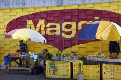 Caraïbes, Ile de la Dominique, la capitale Roseau, marché centrale, étal de fruits et légumes devant une peinture murale publicitaire pou Maggi