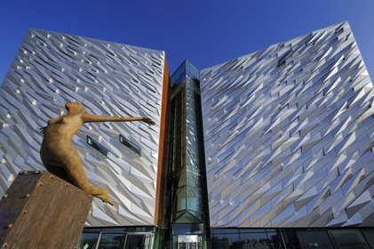 Royaume-Uni, Irlande du Nord, Belfast, quartier des docks de Queen's Island, la sculpture Titanica par l'artiste Rowan Gillespie devant le batiment du centre Titanic Belfast Experience