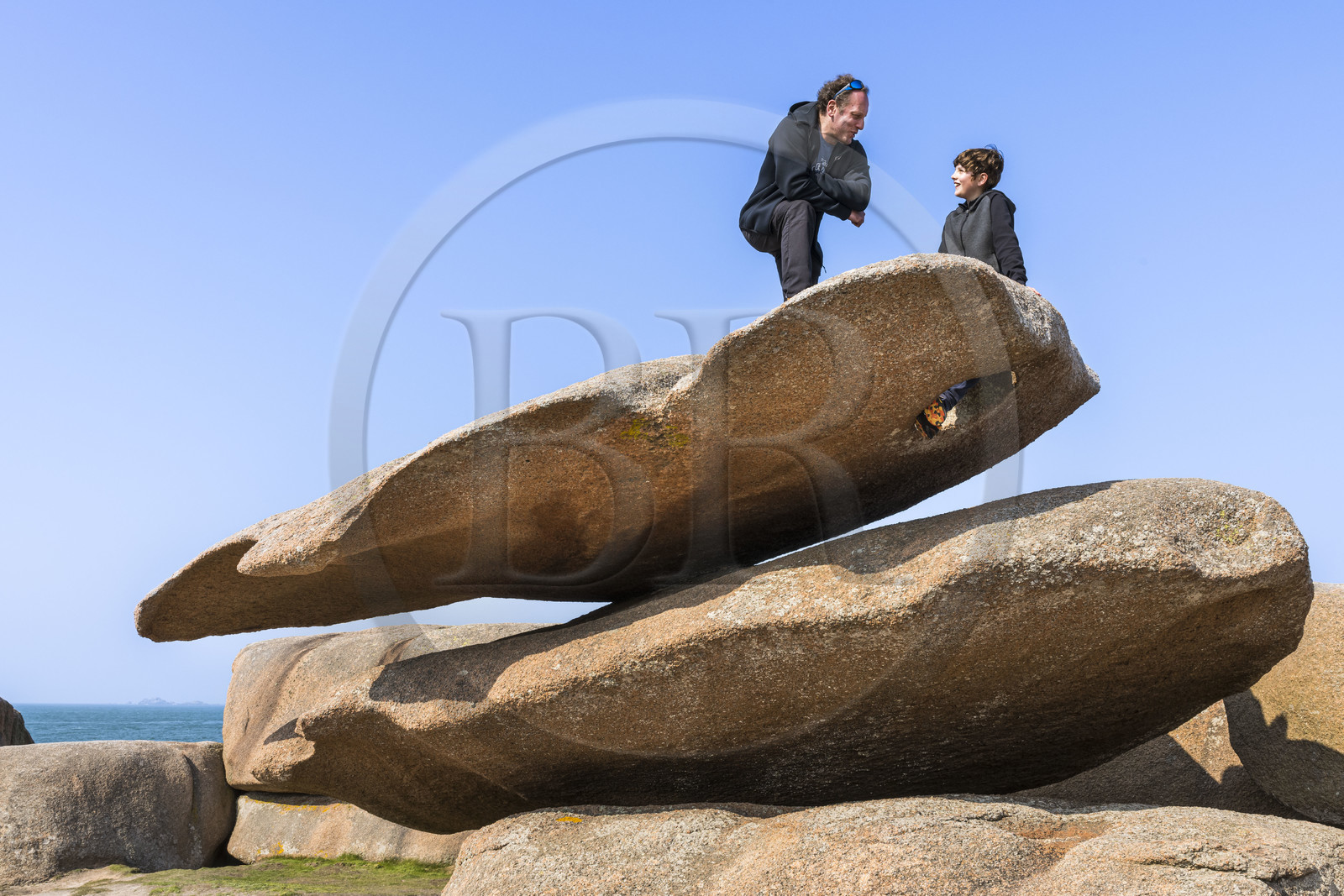 France, Côtes-d'Armor (22), Côte de Granit Rose, Trégastel, Ile Renote, le chaos granitique, Pierre et son fils Alexandre sur le rocher appelé la palette du peintre