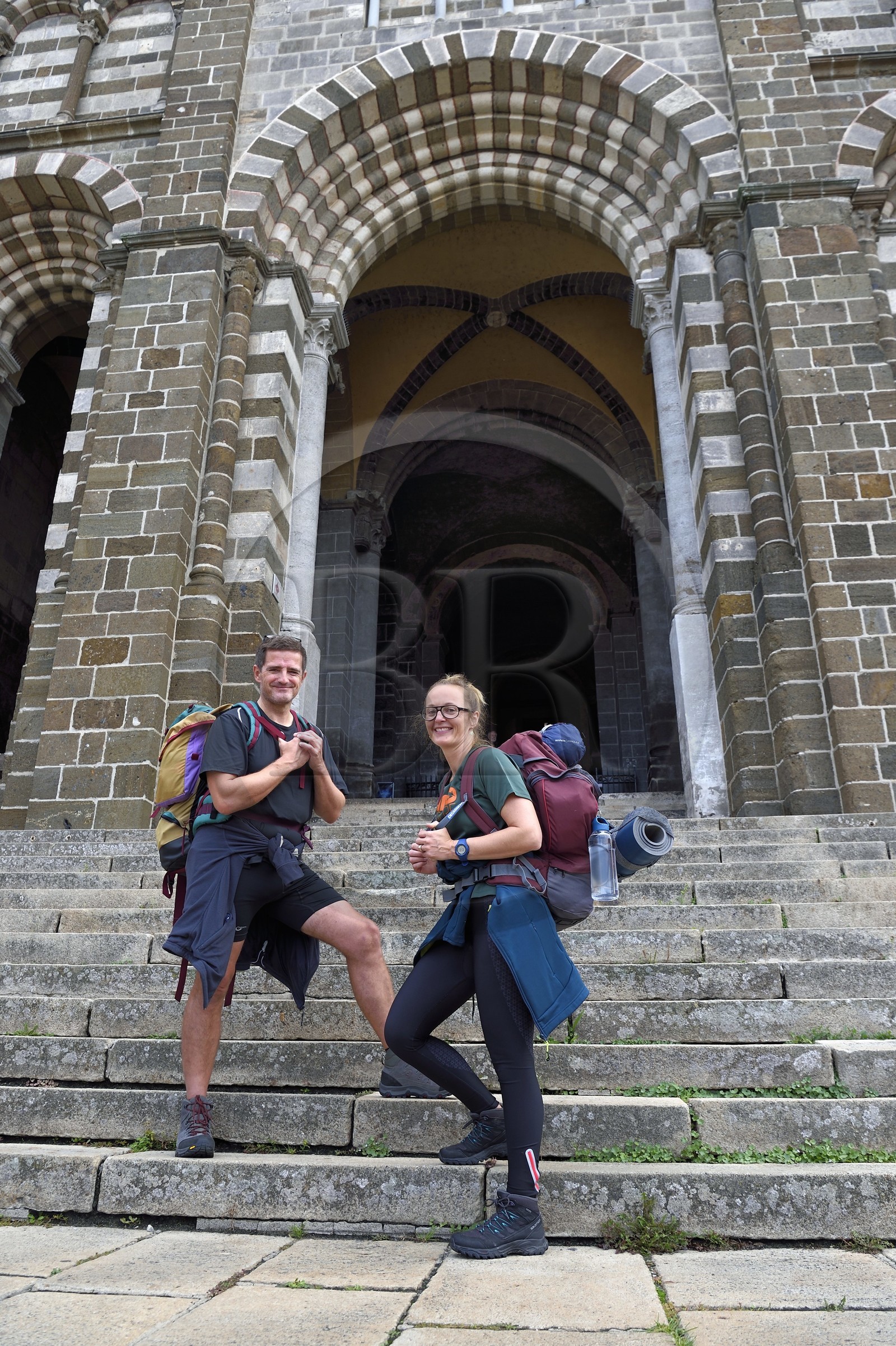 France, Haute-Loire (43), Le Puy-en-Velay, un couple de pélerins en partance sur le chemin de Compostelle devant porche de la cathédrale Notre-Dame-de-l'Annonciation du XIIe siècle classée Patrimoine Mondial de l'UNESCO